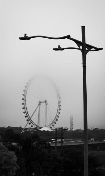 Poste de luz e roda-gigante na neblina